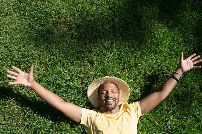 Smiling man in a straw hat relaxes on a lush green lawn, enjoying the results of professional lawn care Rockville MD residents trust.